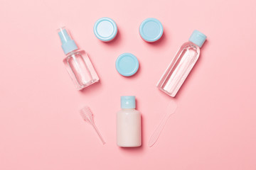 Set of travel size cosmetic bottles on pink background. Flat lay of cream jars. Top view of bodycare style concept