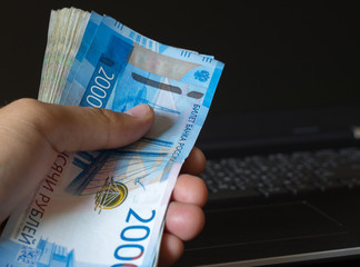 Cash in Russia. Man hand holding a bundle of Russian rubles. Banknotes 2000 rubles.