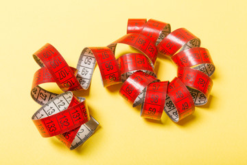 Perspective view of curled measure tape on yellow background. Keeping fit concept