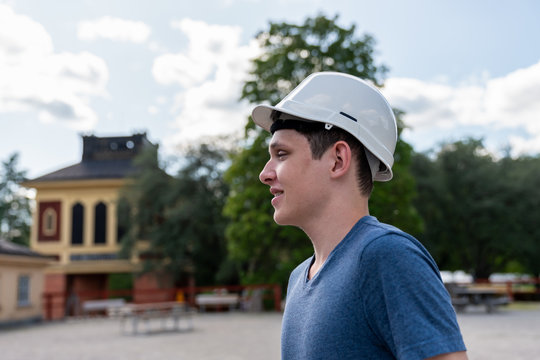 Outdoor profile portrait of a young man wearing a white hard hat. Preparation for underground exploration.