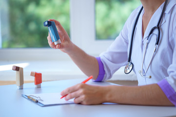 Doctor writes prescription for asthma inhaler to asthmatic patient during medical consultation and...