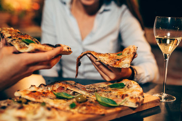 closeup of friends eating pizza