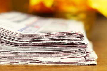 Stack of Newspapers on Wooden Table. Magazines with News Stacked in Pile. Close up view of Tabloid Journals with Headlines and Articles, Focus on Paper. For Business Concept or Background Texture