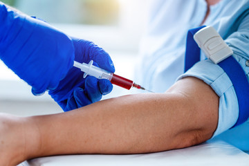 Nurse in rubber blue medical gloves takes blood from a vein for laboratory test. Medical tests