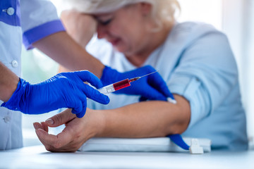 Nurse in rubber blue medical gloves takes blood sample from a vein for laboratory test. Medical...