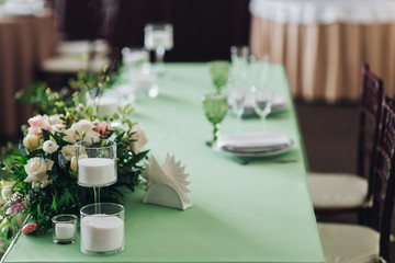 Beautiful composition with flowers on the tables and candles for guests at a wedding or a birthday party