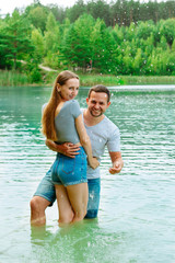 Fototapeta na wymiar Loving couple standing in lake and having fun. Holding hands