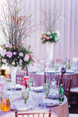 Beautiful composition with flowers on the tables and candles for guests at a wedding or a birthday party