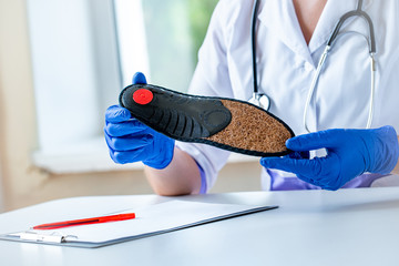 Nurse holds orthopedic insoles for the treatment and prevention of flat feet. Foot care and wearing...