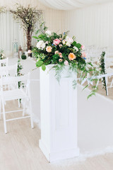 Indoor wedding ceremony with white wedding arch decorated with flowers and big white candles