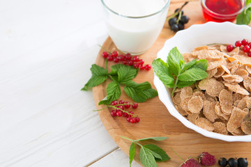 Healthy breakfast with cornflakes and fresh berries on white wooden Healthy tasty breakfast multigrain wholewheat healthy cereals with strawberries, raspberries, black currants and red currants.