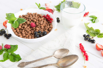 Chocolate cereal balls in bowl and milk. Selective focus Healthy tasty breakfast chocolate balls with strawberries, raspberries, black currants and red currants.