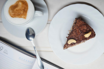 chocolate cake slice with a white cup of tea and a handful