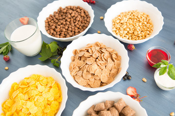 oatmeal with nuts and dried fruits on old white painted wooden table. Perfect breakfast Breakfast cereal mix: cornflakes, pads, muesli, multigrain flakes and chocolate balls