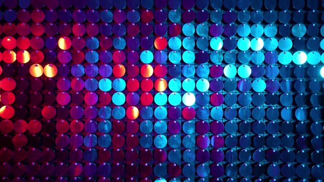 Shiny kinetic surface panel illuminated by pink and blue light in luxury boutique. Flickering background for interruptions or text savers. Mirror sequins sway by wind blowing.
