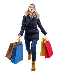 Front view of a happy woman in a jacket with shopping bags that runs.