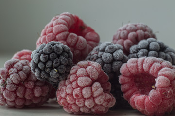 Frozen blackberry and raspberry on gray background close-up