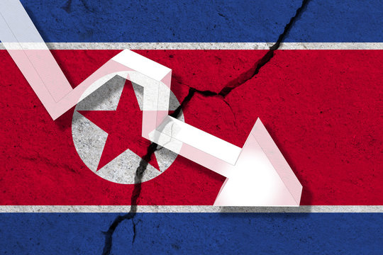 North Korea Flag on the cracked wall with arrow falling down. Concept of decrease in the country.