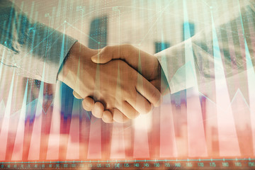 Double exposure of financial graph on cityscape background with two businessman handshake. Concept of stock market deal