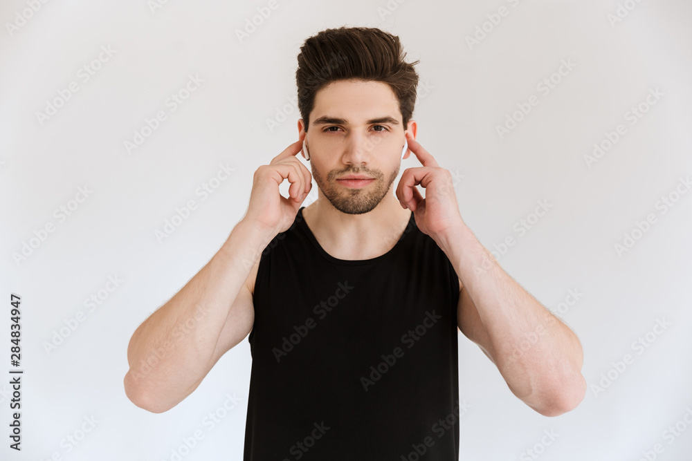 Poster handsome concentrated young sports man isolated over white wall background listening music with earp