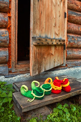 Shoes fabulous creatures standing on the threshold of a wooden house near the open door.