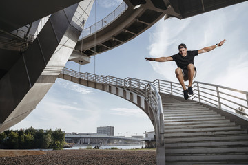 Parkour athlete doing a beautiful high jump from the stairs