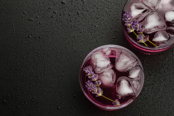 Lavender lemonade with ice on wet black background
