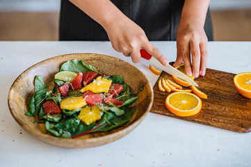 Crop hand passing green salad in white bowl while friends eating together