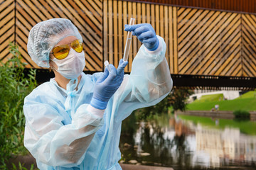 female ecologist or epidemiologist checks water quality in urban pond