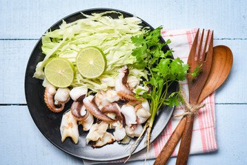 Grilled squid salad with lime herbs and spices on dining table - Tentacles octopus cooked appetizer food hot and spicy seafood cooked served on plate in the restaurant