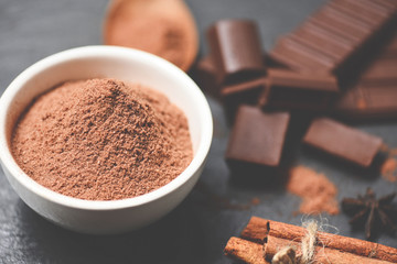 Chocolate powder on bowl and candy sweet dessert for snack - chocolate bar and spice on dark background , selective focus