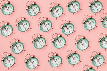 Daylight savings time concept. Set your clocks back with this flat lay retro beautiful alarm clocks set to 2 am over pink background. Pattern. Top view.