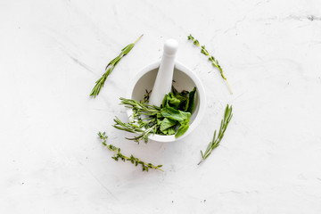 Homeopathy with leaves and healing herbs for making oil on white marble background top view