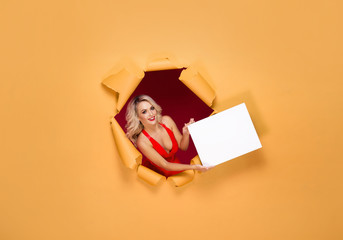 Young and beautiful blond woman in a red dress over yellow torn paper background. Fall, autumn sales, shopping and discount.