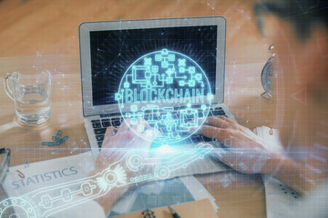 Blockchain theme hologram with man working on computer on background. Concept of crypto chain. Double exposure.