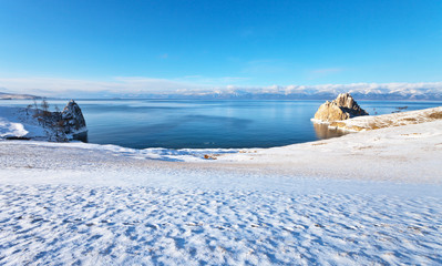 Baikal Lake in a sunny December morning after a snowfall. View of the Khuzhir Bay, Cape Burhan and the Shamanka Rock. Beautiful winter landscape