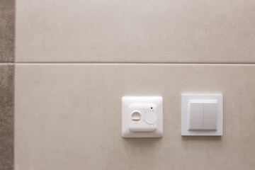 White temperature controller of a warm floor on a gray wall.