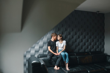 Obraz na płótnie Canvas Loving couple embracing on the couch at home clothes. Cute couple in love in the weekend morning. They are hugging on the sofa indoors at home, wearing casual outfits