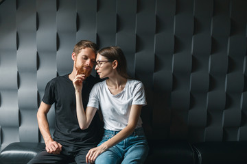 Amazing couple sitting on thesofa near the window and kiss one another. Love story, family in dak loft interior