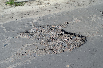 Poor condition of the road surface. Summer season. Hole in the asphalt, risk of movement by car, bad asphalt, dangerous road, potholes in asphalt.  Kiev,Ukraine