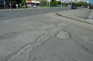 Poor condition of the road surface. Summer season. Hole in the asphalt, risk of movement by car, bad asphalt, dangerous road, potholes in asphalt.  Kiev,Ukraine