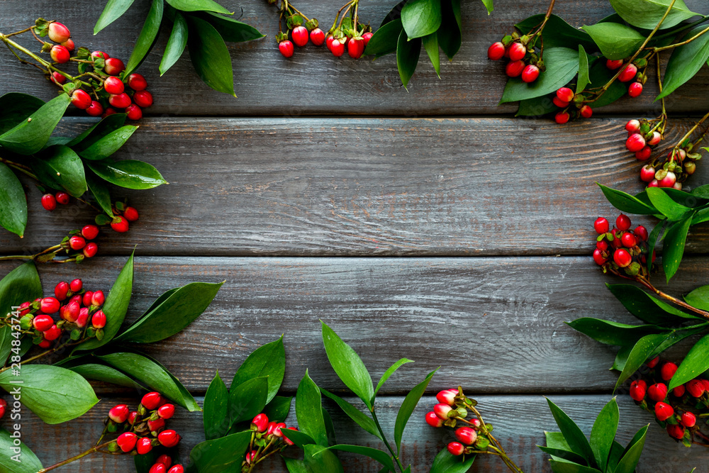 Wall mural green herbs and red berries for summer design on wooden background top view mock up