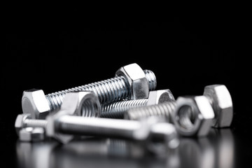 Steel nuts and bolts close-up. Bolts and nuts on a black background. - obrazy, fototapety, plakaty