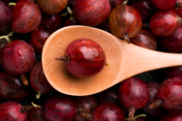 Gooseberries in a wooden spoon. Gooseberries and a wooden spoon on the table.