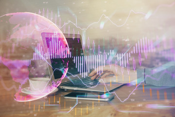 Double exposure of businessman's hands with laptop and stock market graph background. Concept of research and trading.