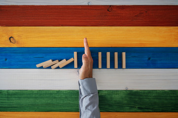 Hand of a businessman stopping falling dominos