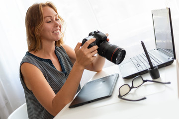 Naklejka premium A young woman photographer sitting at his Desk and working with a camera. Close up