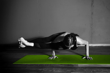 Black white photo of Young beautiful woman brunette in black clothes practice yoga in dark studio green mat Sport meditation monochrome