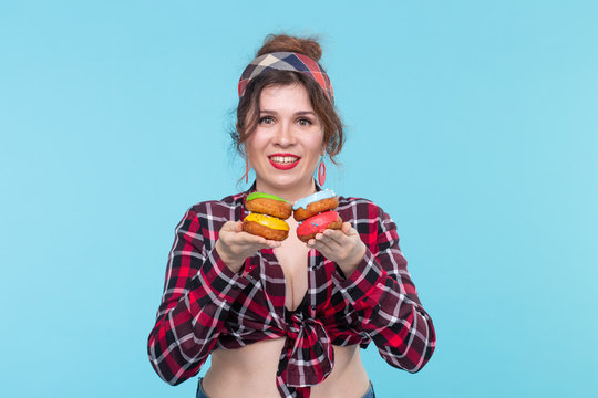 Cheerful beautiful young woman in a plaid shirt holds in her hands the four multicolored tips posing on a blue background. Concept of home baking and desserts.