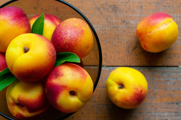 Nectarines with leaves on a wooden background. Summer fruits. Food photo. View from above.